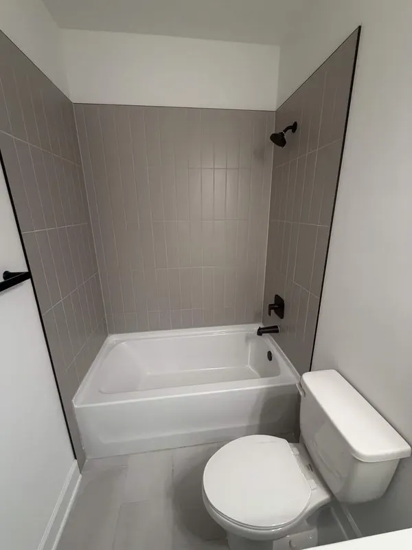 Vertical dark gray tile shower with matte black fixtures, Jacksonville remodel